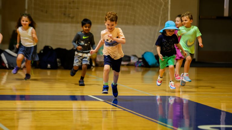 A photo with a young boy as the focus, during an All-Sports program overview activity inside a gymnasium