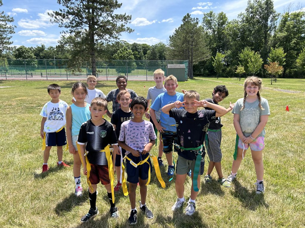 A group of young campers outside during a sunny day during one of their sports programs.