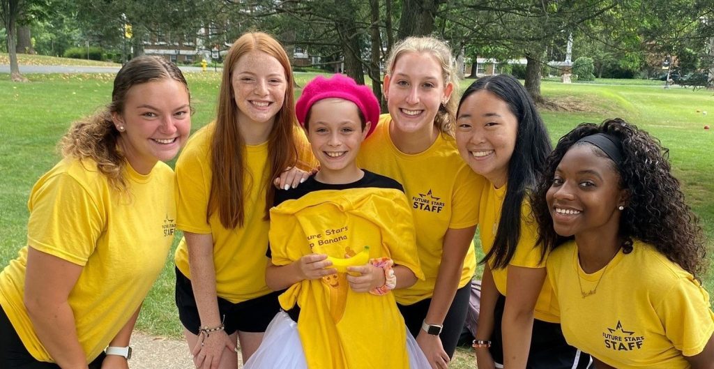 a young camper surrounded by young camp counselors