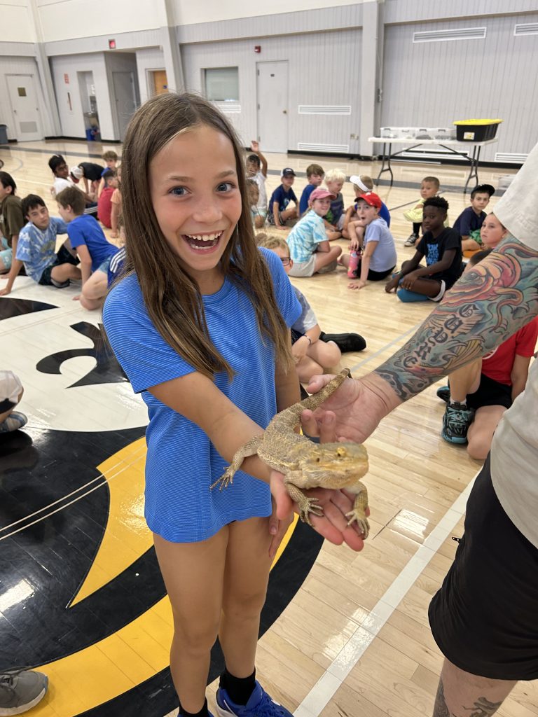 a young girl smiling while holding a reptile in her hands